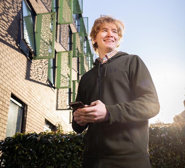 A student smiling in front of The Green accommodation.