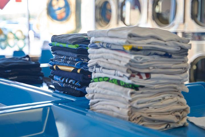 Laundry folded up neatly and stacked in a blue tray.