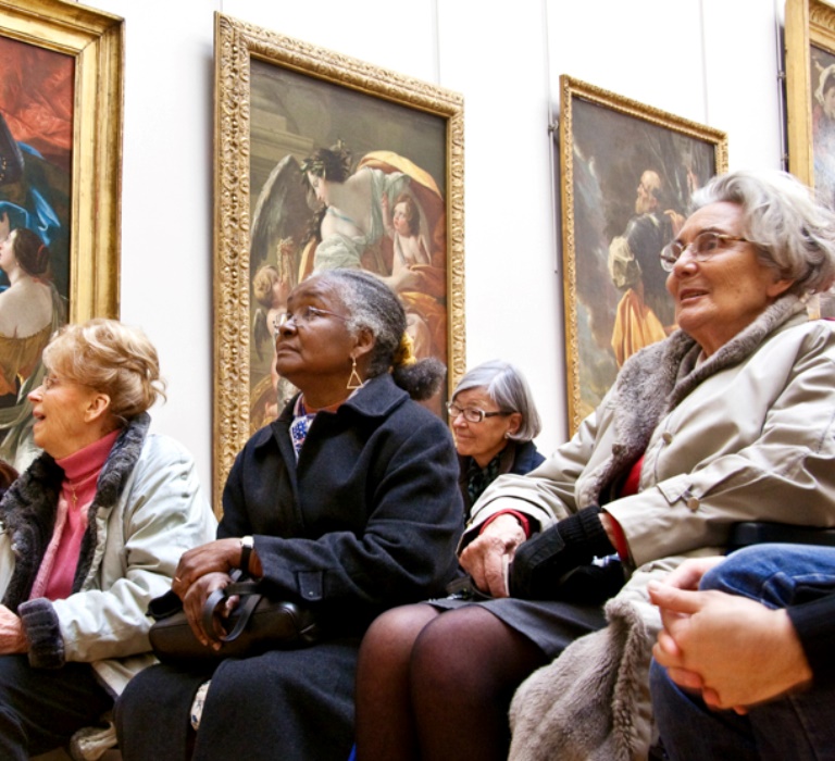 A group of people sat in rows facing the same direction watching and listening