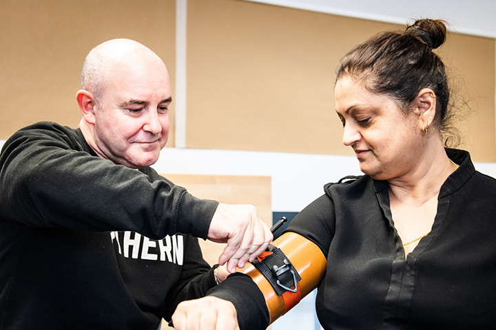 Two people trying on first aid kit that tests blood pressure