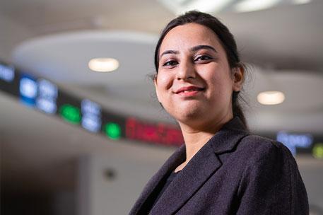 A postgraduate student in the Management building. They are looking down and smiling at the camera.