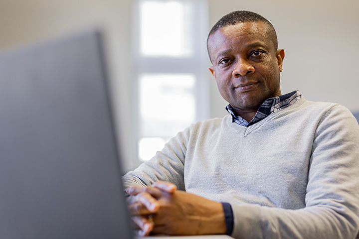 A student sat in front of a laptop smiling at the camera