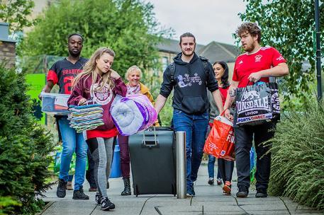 Four students walking and carrying their belongings.