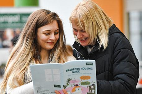 A student looking at a housing leaflet with their parent/carer.