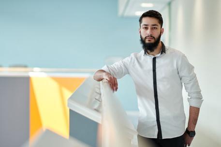 A student leaning on a railing and looking at the camera