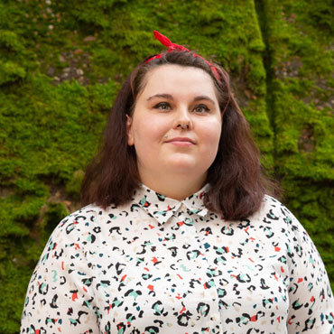 A student standing in front of a mossy wall