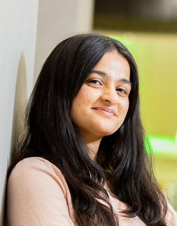 A student standing in the Richmond atrium at the University of Bradford smiling at the camera