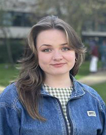 A student standing outside on campus at the University of Bradford