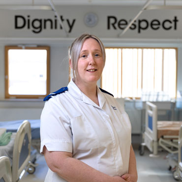 A student in a nursing uniform smiling at the camera