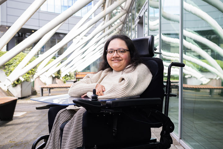 A student smiling at the camera in the atrium of the Richmond Building at the University of Bradford