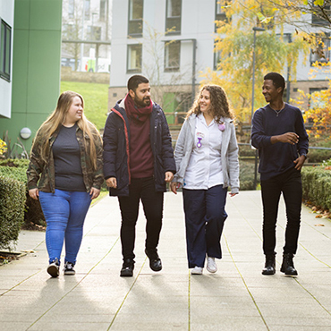 Four students walking through The Green on-campus student village