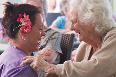 A student nurse and elderly patient laughing together