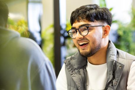 Student wearing glasses and smiling at their friend