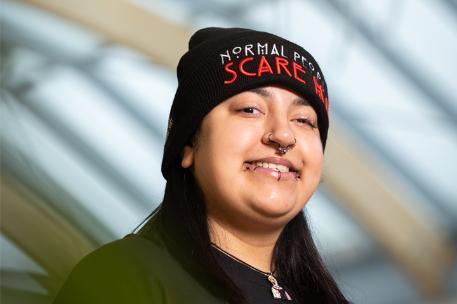 Student with piercings wearing a hat and smiling
