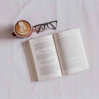 An open book on a table with a pair of glasses