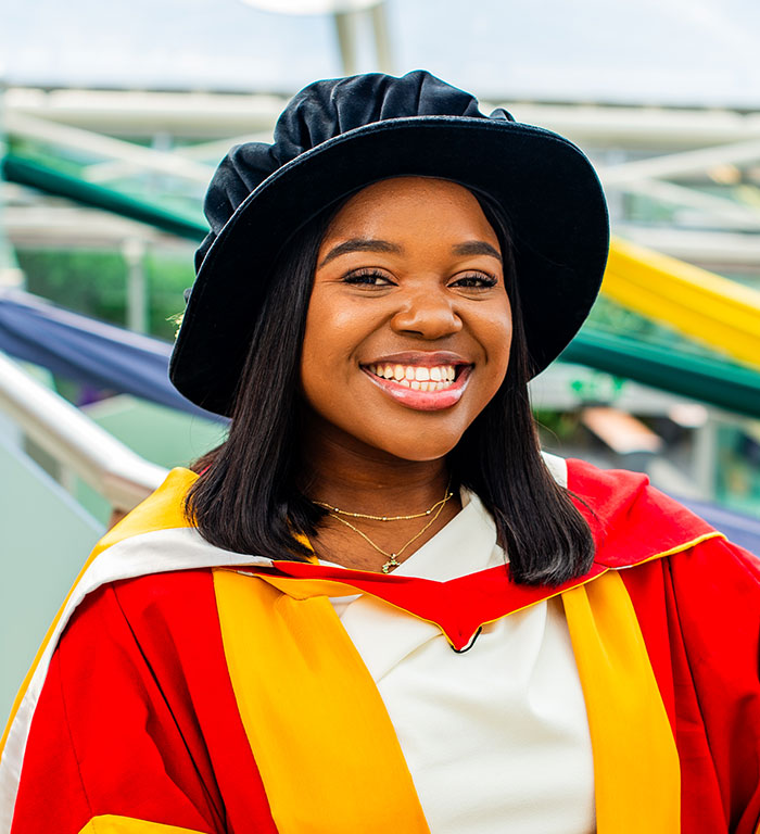 Vee Kativhu, Doctor of the University (2024) posing in a gown at ceremonies