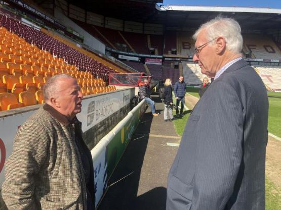 posite each other talking at an empty football stadium