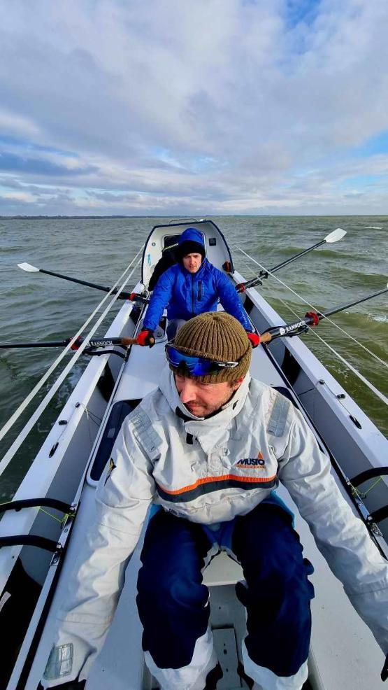 a close-up photo of two people sat behind each other on a boat