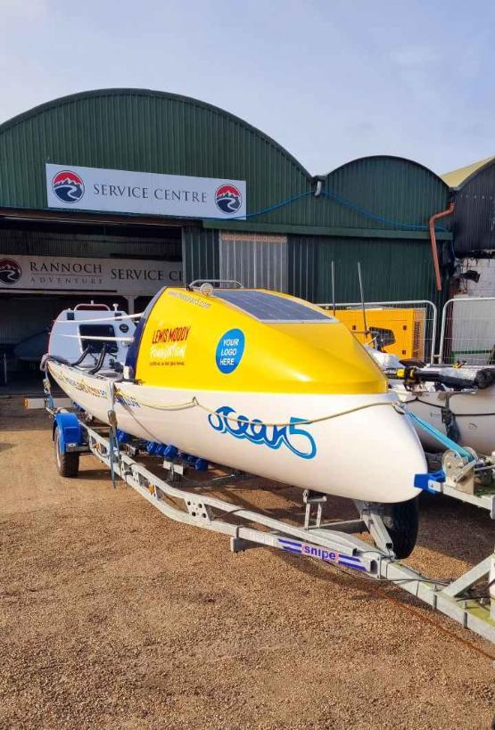 A boat which is white coloured on the bottom half and yellow at the top half which is on land