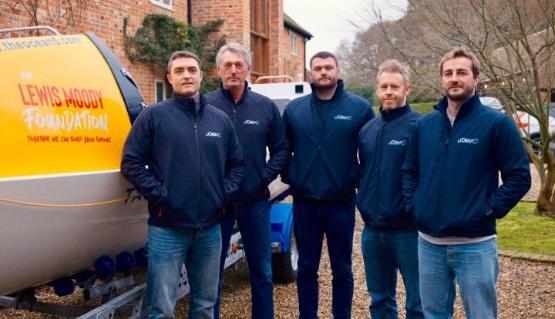 Four people standing up outside wearing the same jumper and jeans