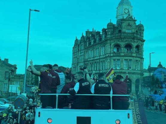 A close up photo of the upper deck of a double decker bus filled with people wearing tracksuits