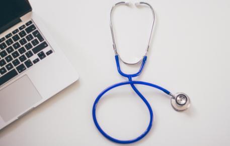 A laptop and a stethoscope on a desk