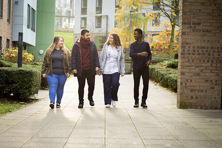 Four students walking through The Green on-campus student village