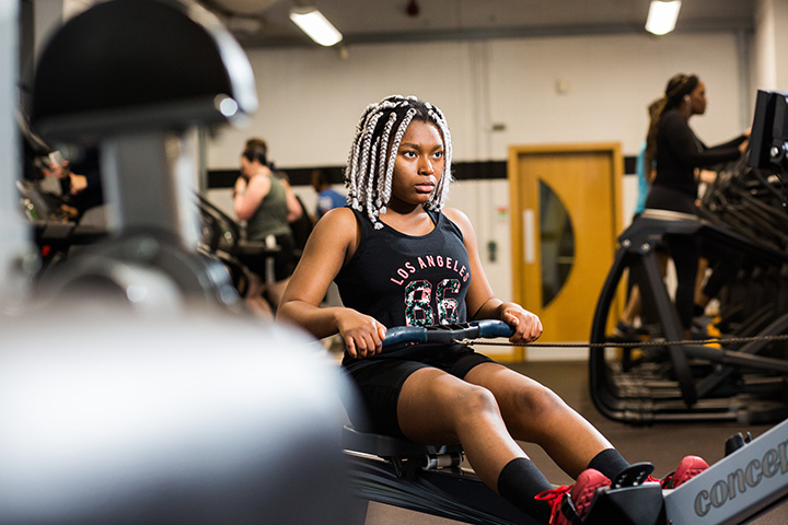 Student using rowing machine at the on campus gym, Unique Fitness