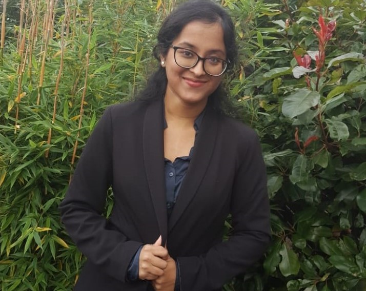 Above the waist shot of Sapna stood in front of some greenery.