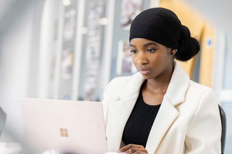 A student sitting at a desk working on a laptop.